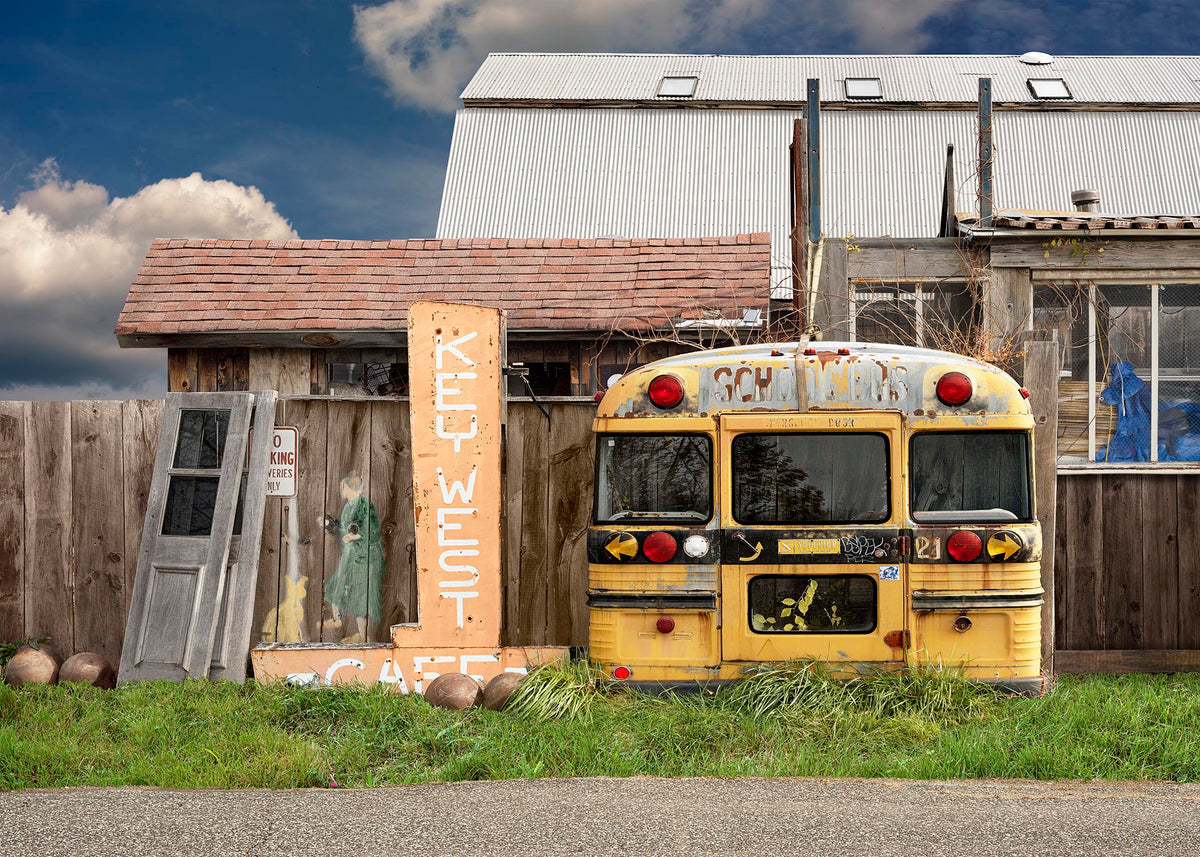 An environmental landscape photography print of the vintage yellow Key West Cafe sign and a school bus backend in the Berkshires.