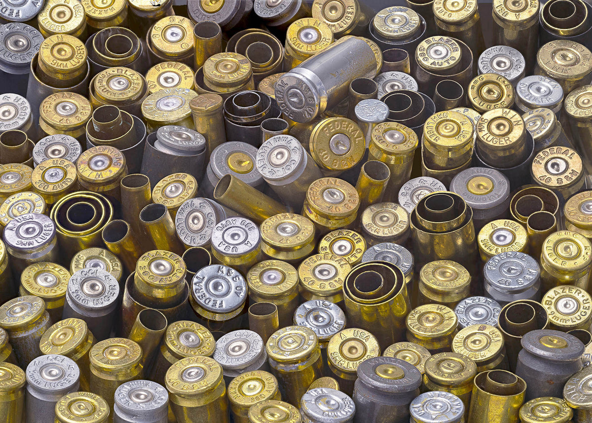 A high-resolution, detailed collage print of spent brass and silver bullet casings with stamped manufacturer markings.